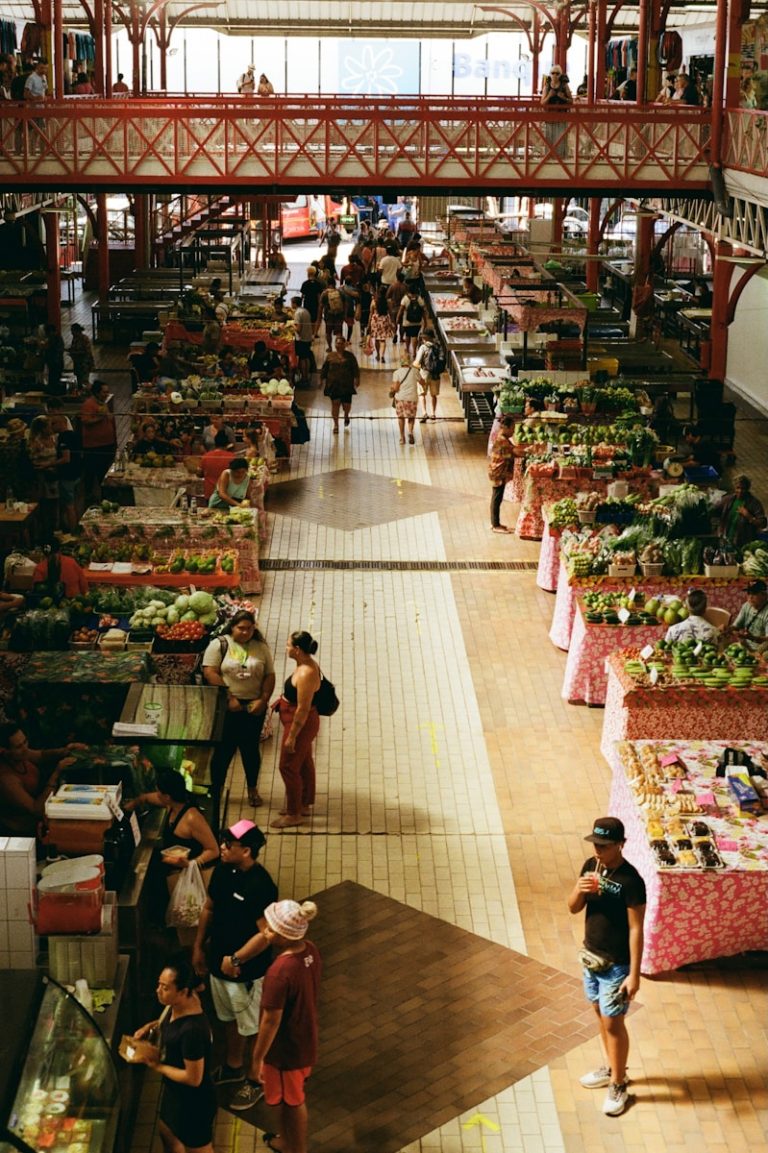 People shop at an indoor market with many stalls.